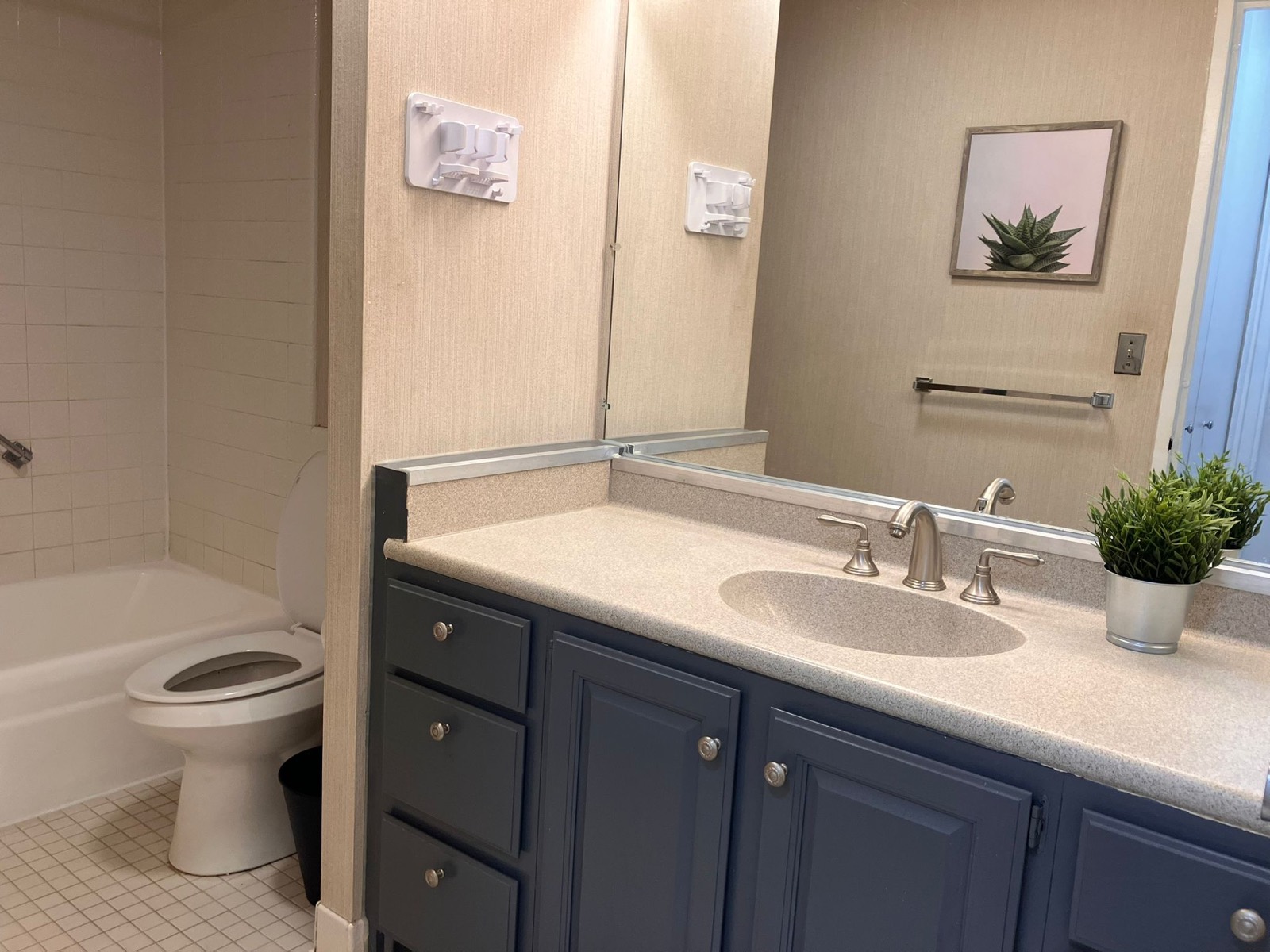 A bathroom with a blue vanity, a white tub, and a glass shower.