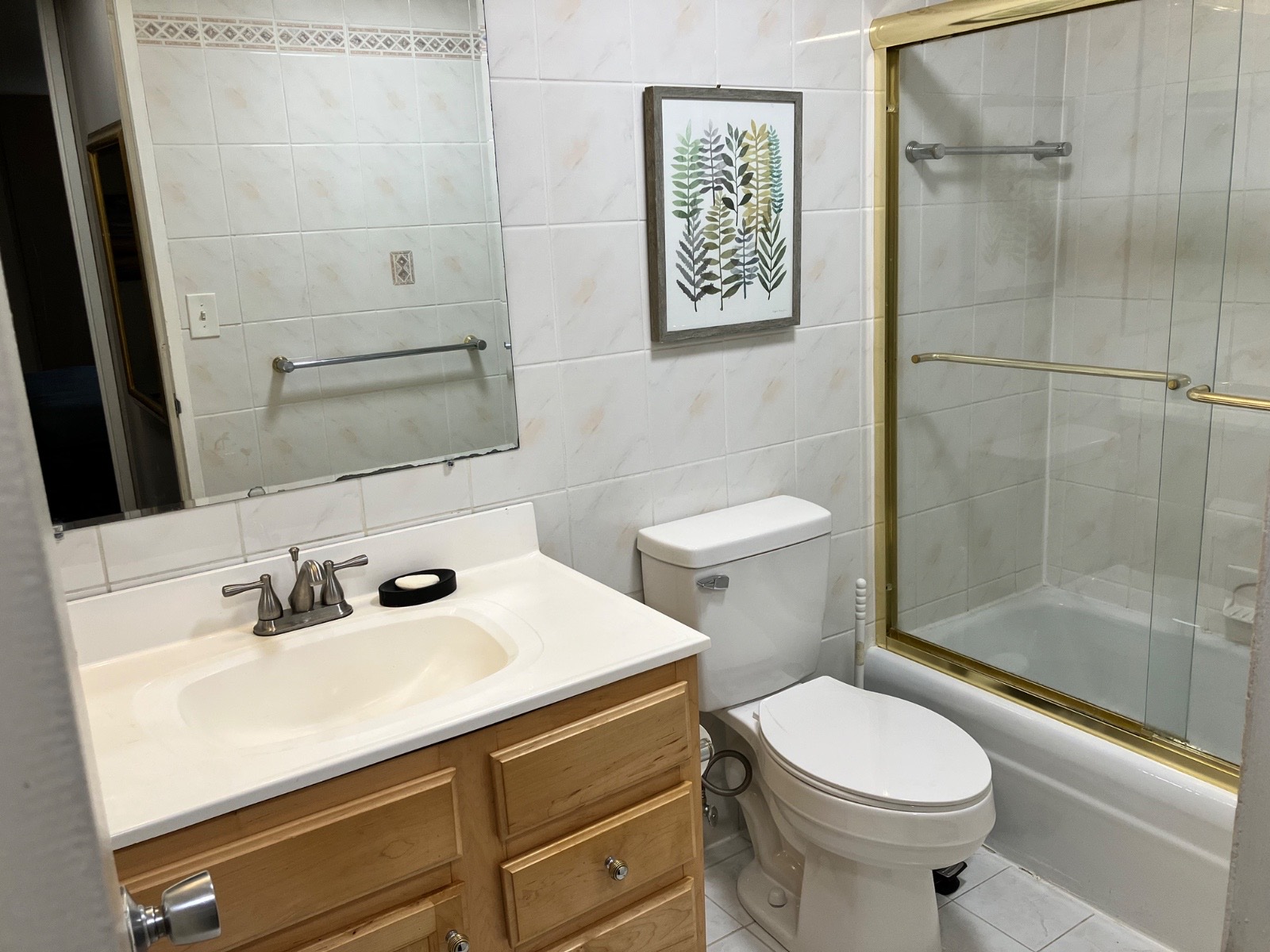 A bathroom with a wood vanity, a white tile shower, and a tub.