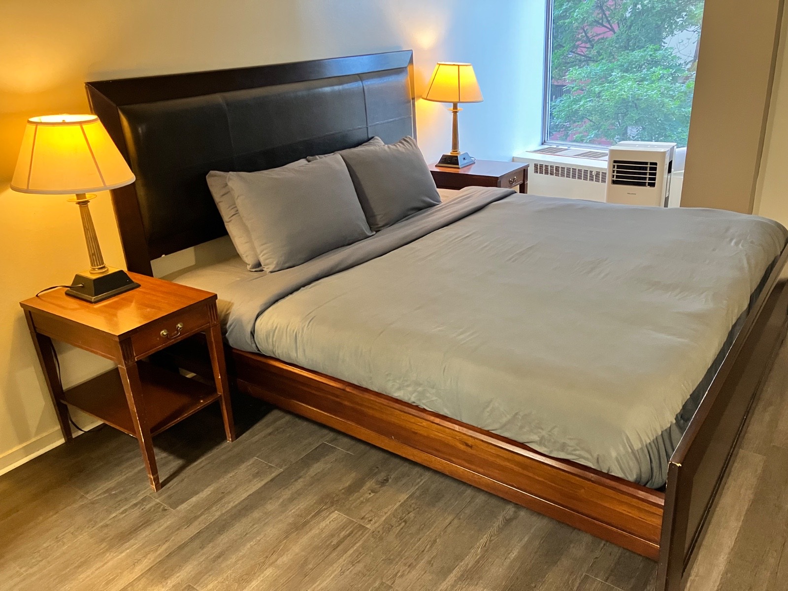 A bedroom with a wood bed, gray bedding, and a window.