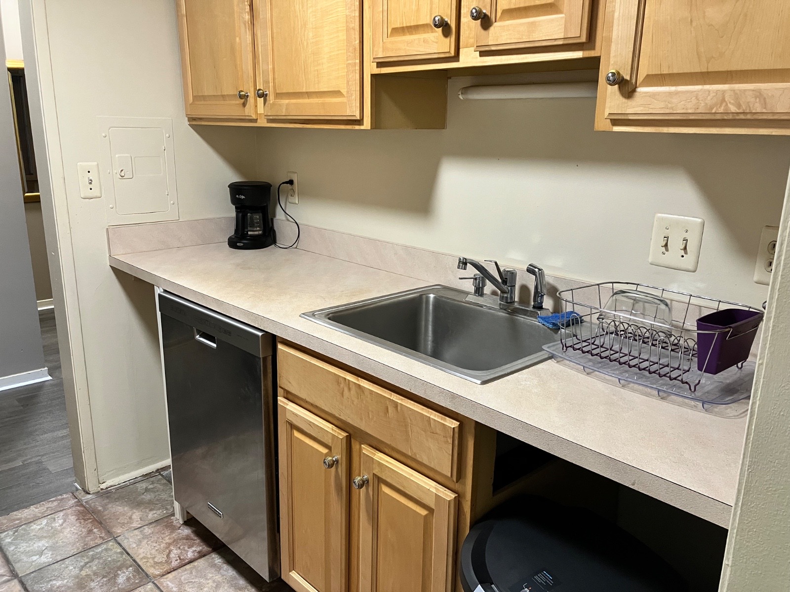 A kitchen with light wood cabinets, a sink, a dishwasher, and a stove.